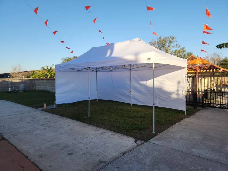 White pop-up tent with sidewalls on a lawn